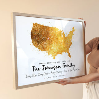 Person holding a framed map of the United States with gold accents and text.