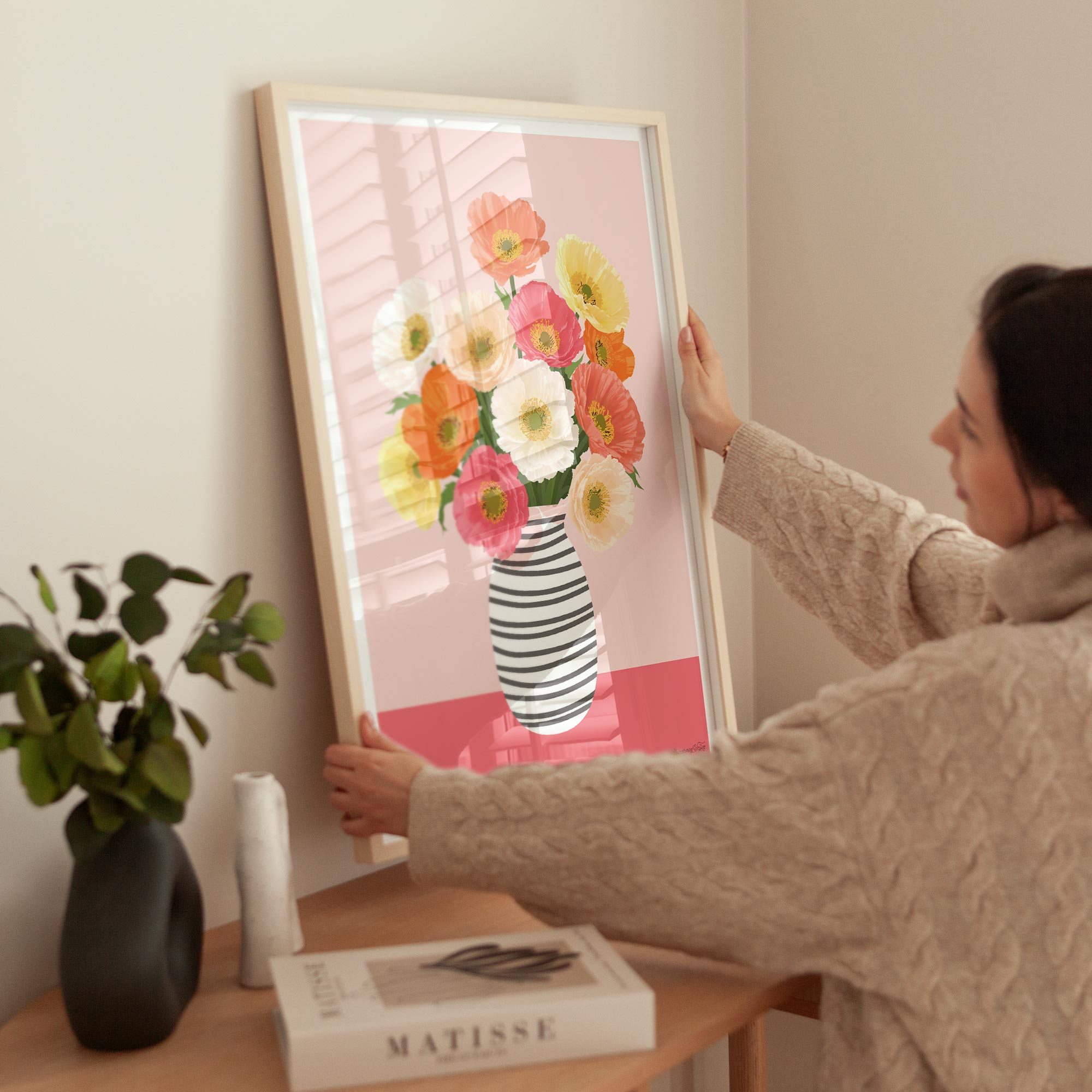 Person hanging a framed floral print on a wall