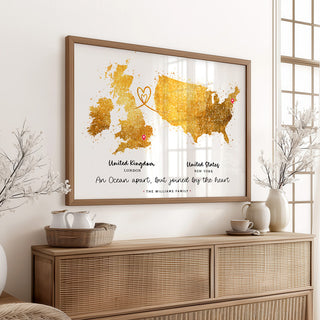 Framed map of United Kingdom and United States with heart design on a wall above a wooden sideboard.