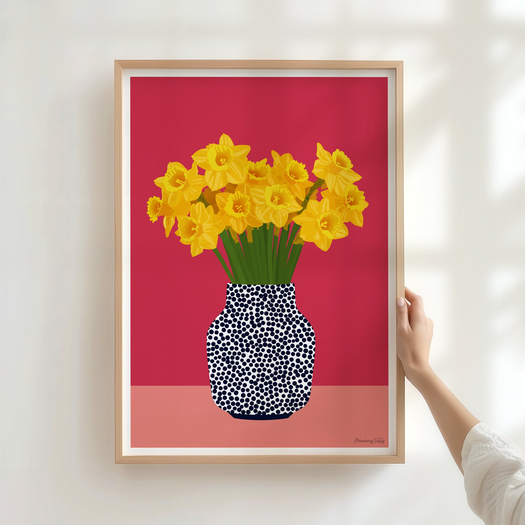 Framed artwork of yellow flowers in a polka dot vase on a red background